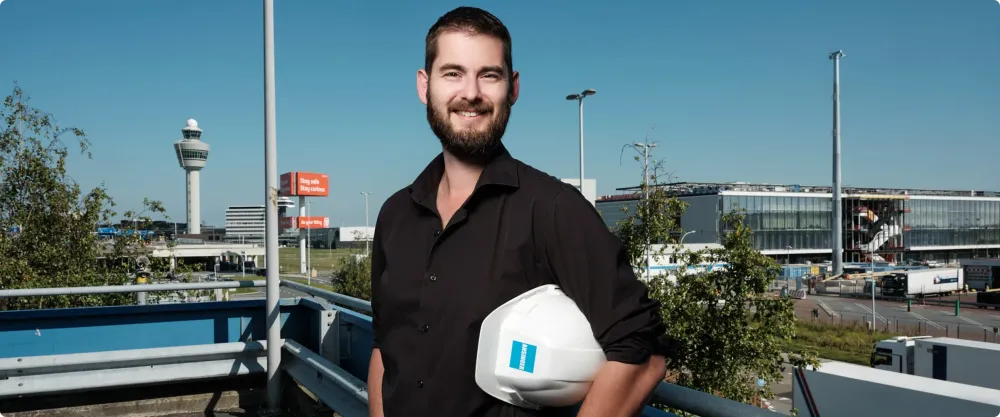 Lachende professional met bouwhelm op een viaduct langs de snelweg