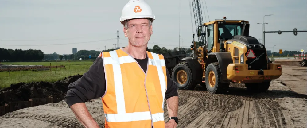 Professional met helm en veiligheidshesje voor een shovel op een bouwterrein